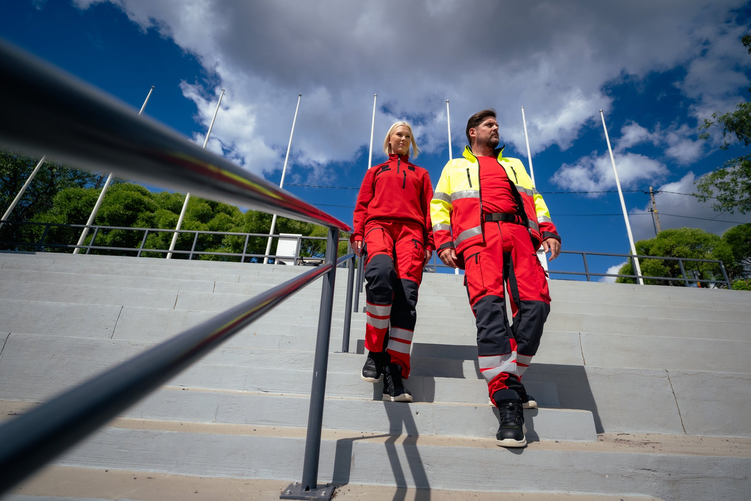 Kuvassa mies ja nainen kävelevät ulkona rappuja alas. Molemmilla on päällään Image Wearin Lanssi-malliston tuotteita ensihoitajille.