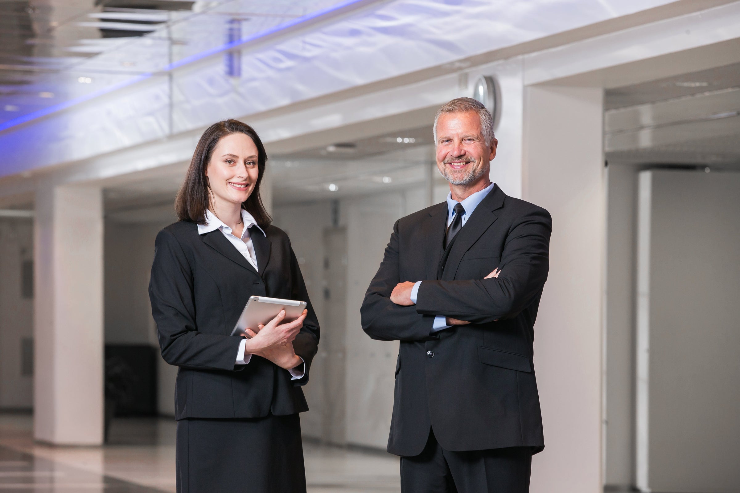 Kuvassa nainen ja mies seisovat portaikossa. Molemmilla on päällä Image Wearin malliston suorat mustat housut. Miehellä on lisäksi  musta puvun takki  ja kauluspaita sekä solmio. Naisella on tummansininen villatakki ja vaaleansininen paitapusero.