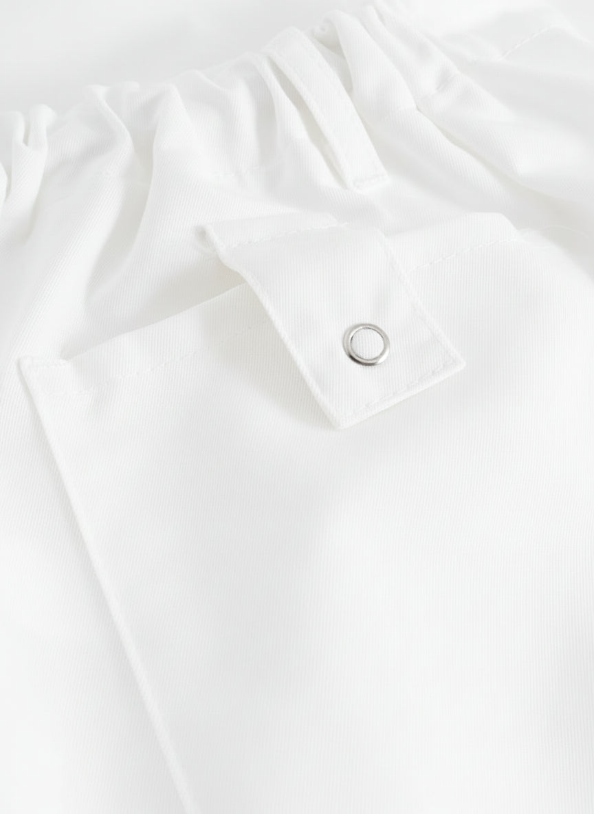 Yksityiskohtakuva valkoisten työhousujen taskun läpästä.