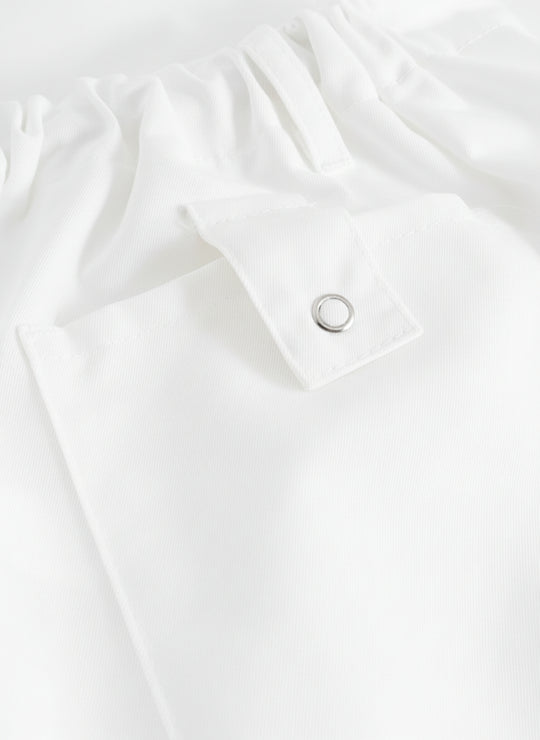 Yksityiskohtakuva valkoisten työhousujen taskun läpästä.