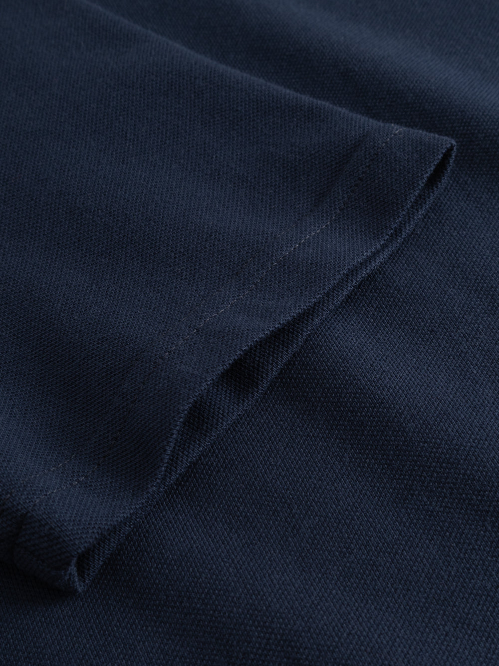 Yksityiskohtakuva tummansinisen naisten pikeepaidan hihansuusta.