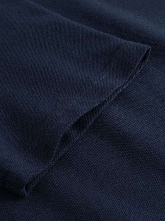 Yksityiskohtakuva tummansinisen naisten pikeepaidan hihansuusta.