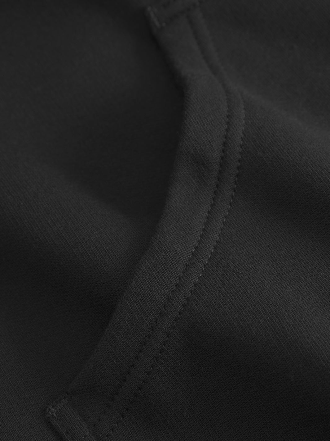 Yksityiskohtakuva mustan collegetakin taskunsuusta.