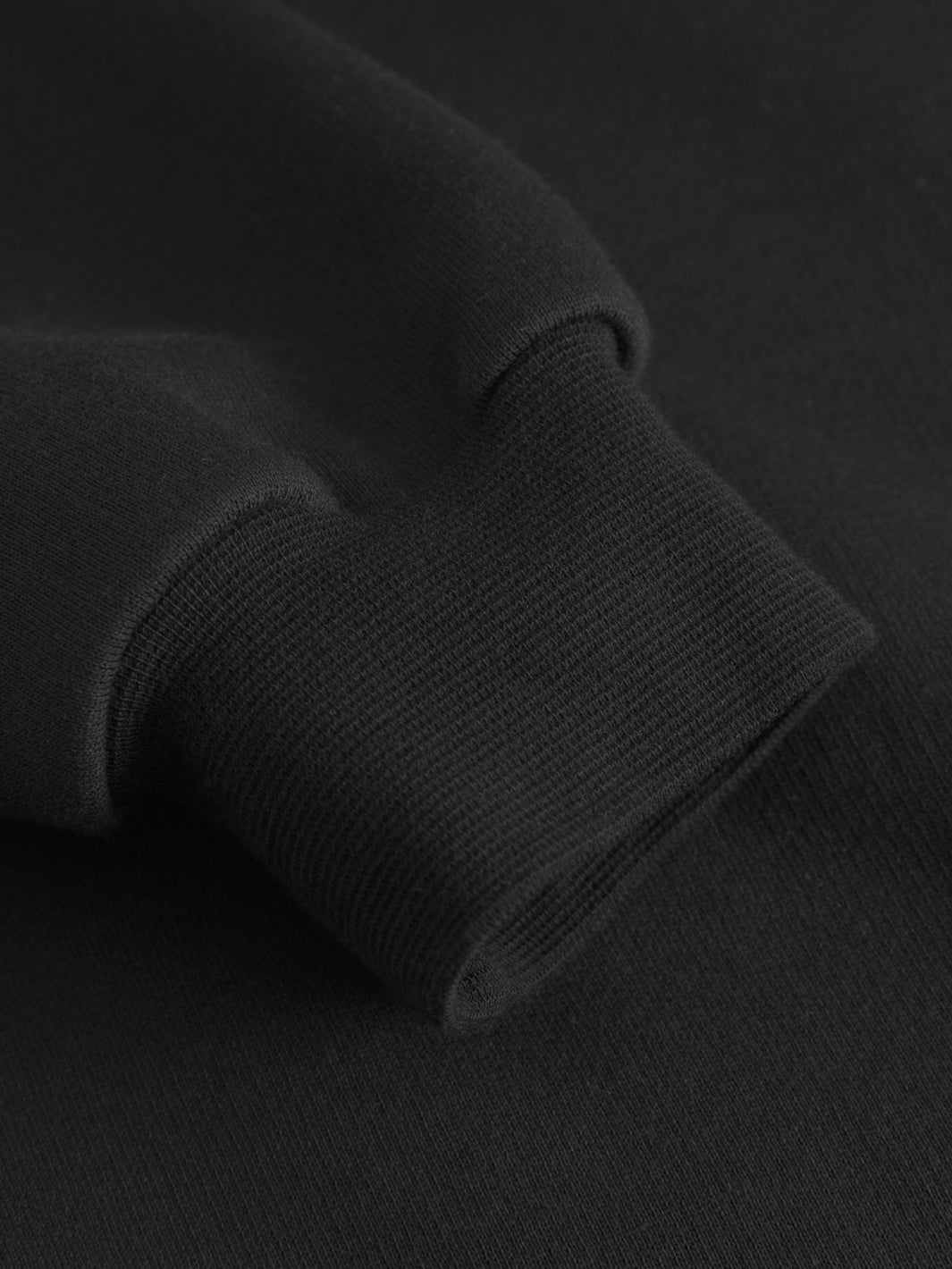 Yksityiskohtakuva mustan collegetakin hihansuun resorista.