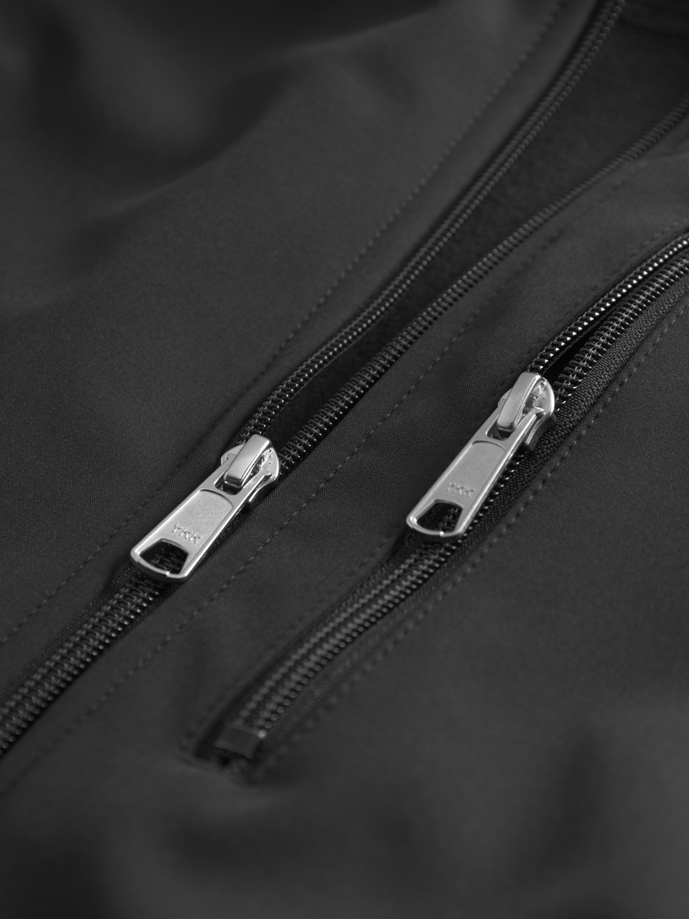 Yksityiskohtakuva softshell-takin etuvetoketjusta ja taskun vetoketjusta.