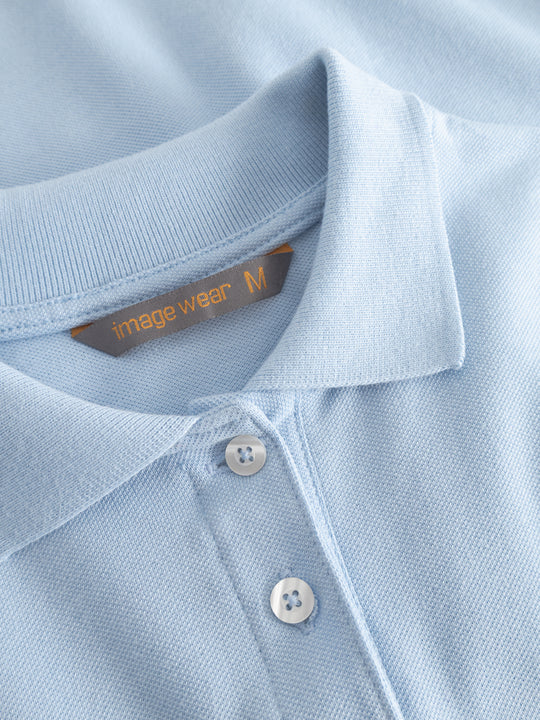 Yksityiskohtakuva vaaleansinisen naisten pikeepaidan kauluksesta ja Image Wearin tuotemerkistä.