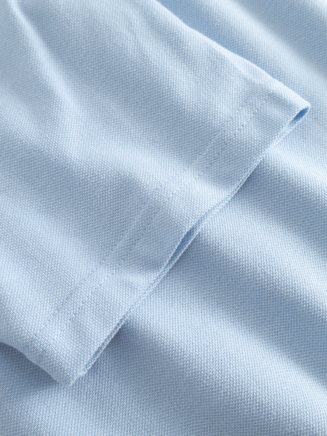 Yksityiskohtakuva vaaleansinisen naisten pikeepaidan hihansuusta.