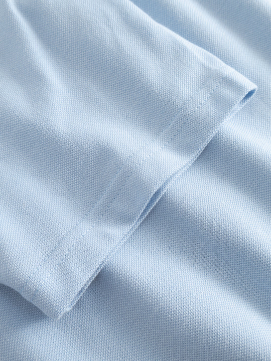 Yksityiskohtakuva vaaleansinisen naisten pikeepaidan hihansuusta.