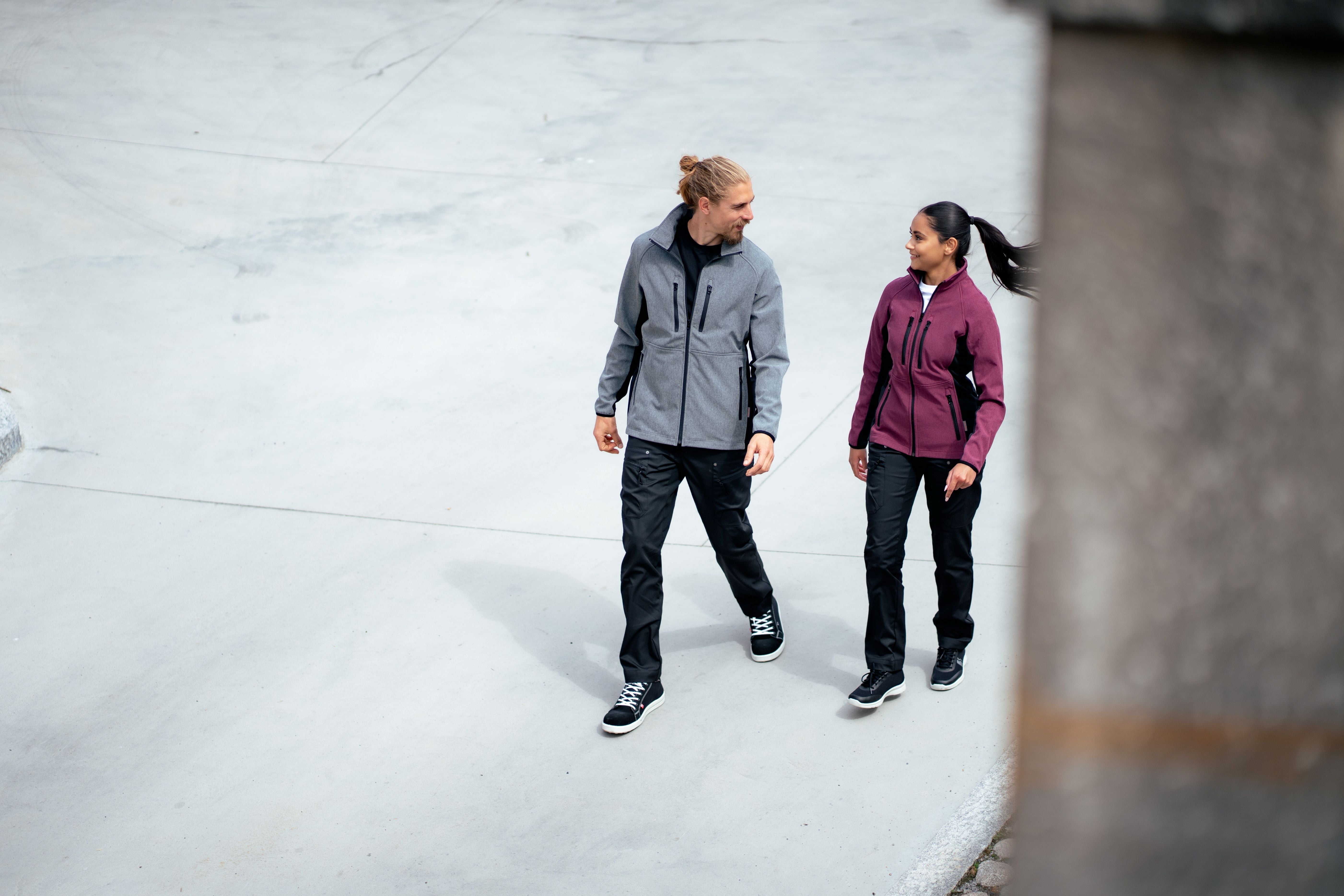 Miehellä ja naisella on kuvassa päällä Image Wearin Softshell-takit Vire mallistosta, mustat joustohousut sekä trikoopaidat. 