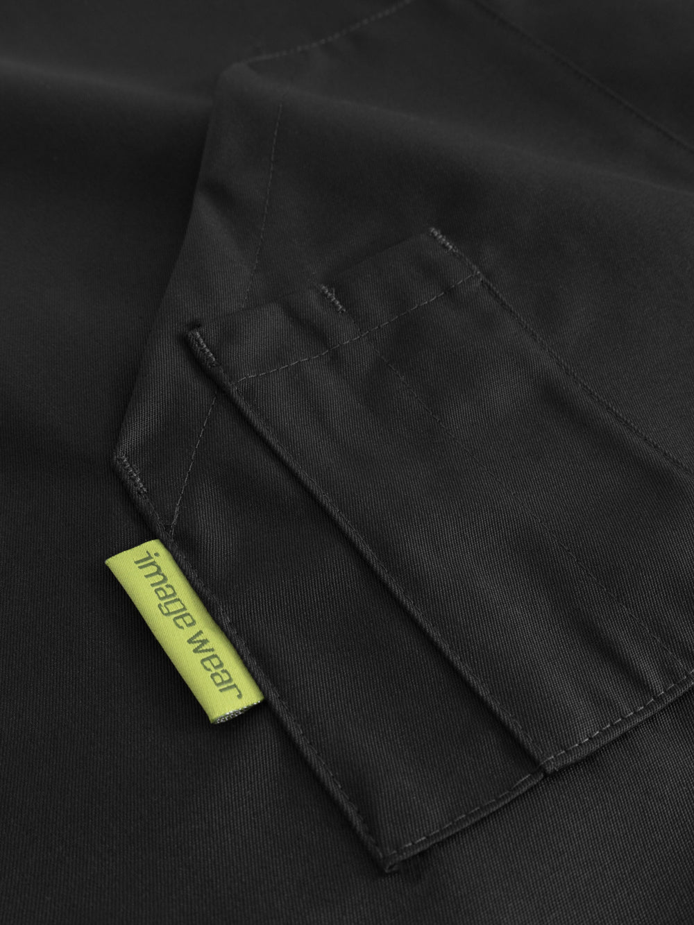 Yksityiskohtakuva mustan pitkän esiliinan taskusta ja kynätaskusta. 