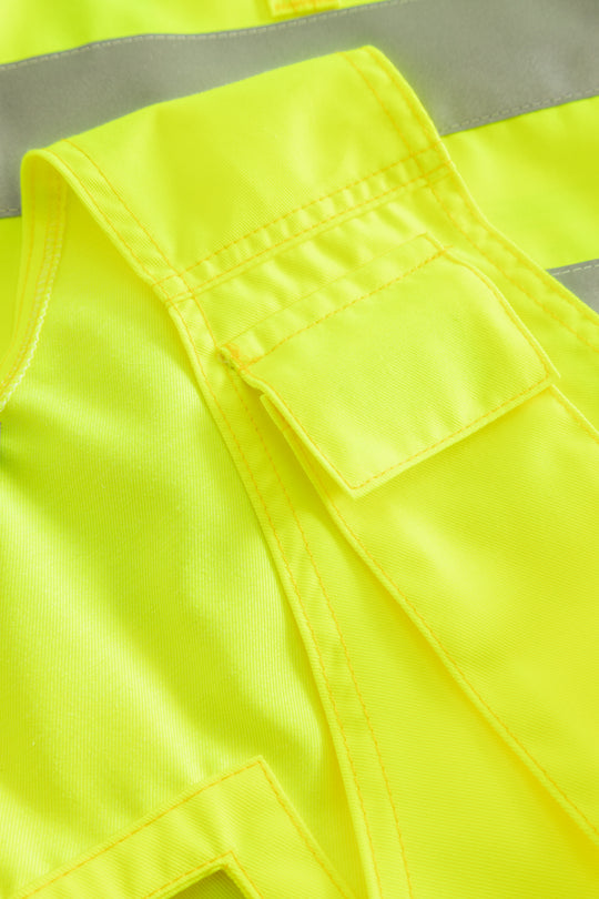 Yksityiskohtakuva keltaisen varoitusriipputaskuliivin puhelintaskusta. 