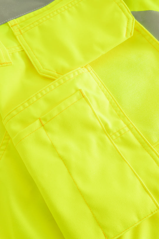 Yksityiskohtakuva keltaisen varoitusriipputaskuliivin taskuista. 