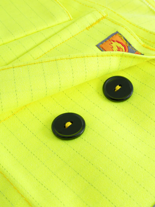 Yksityiskohtakuva keltaisen palosuojatun riipputaskuliivin napillisesta taskusta ja antiflame merkistä. 