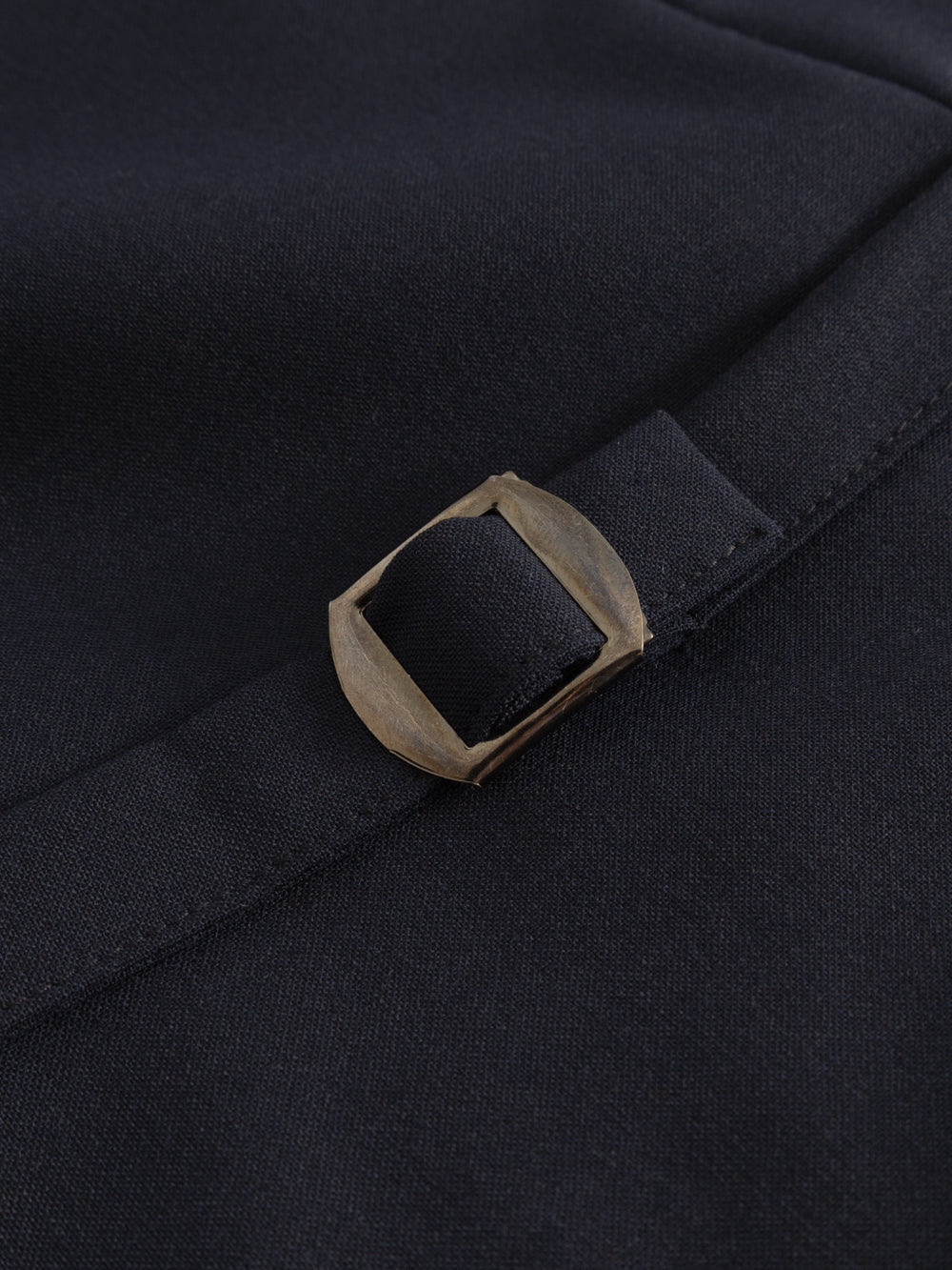 Yksityiskohtakuva tummansinisen liivin takana olevasta säädettävästä tampista. 