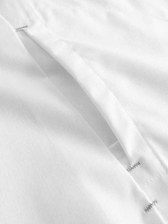 Yksityiskohtakuva valkoisen naisten toimipaikka/hoitajan työpaidan taskunsuusta.