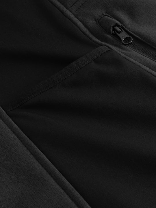 Yksityiskohtakuva meleeratun mustan softshell-liivin sivuosasta. 