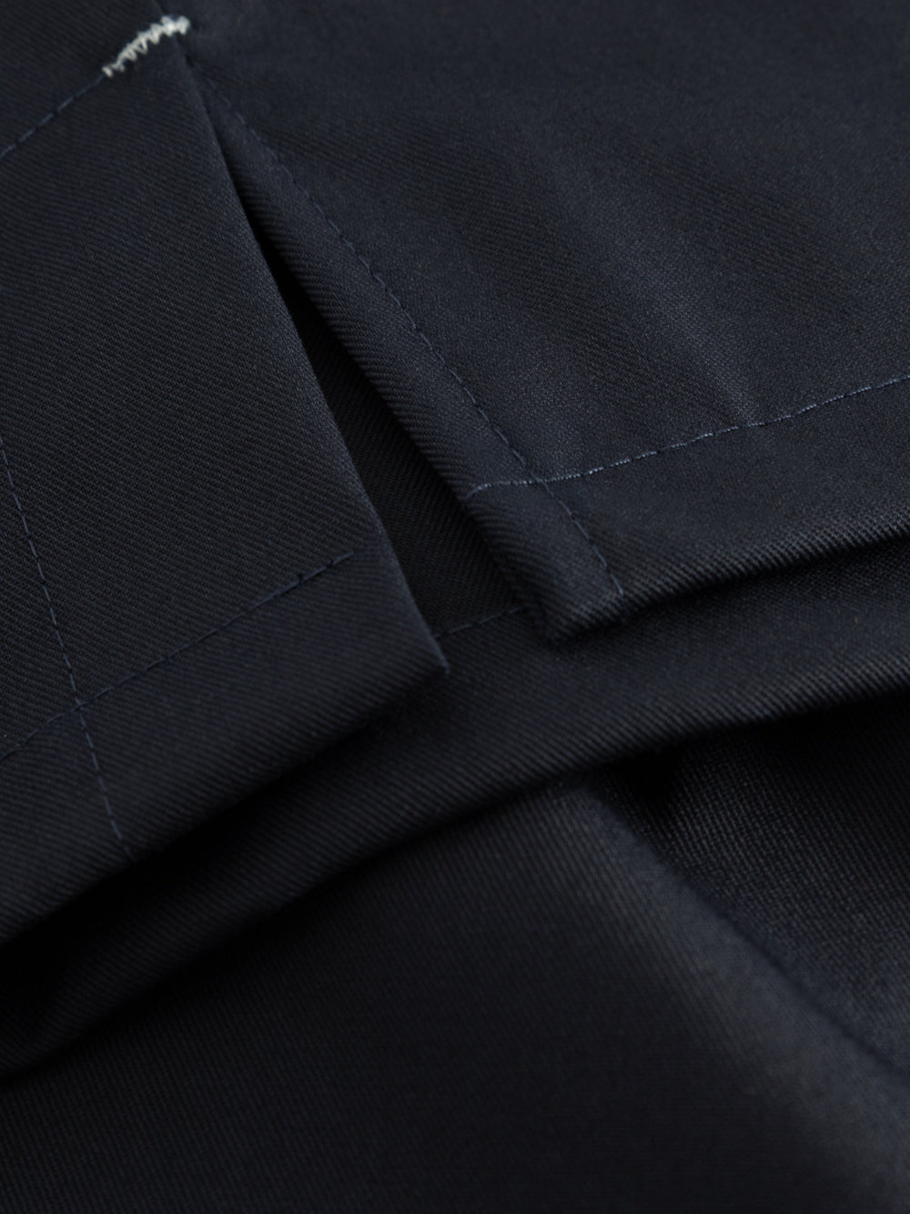 Yksityiskohtakuva tummansinisen työliivin sivuhalkiosta. 