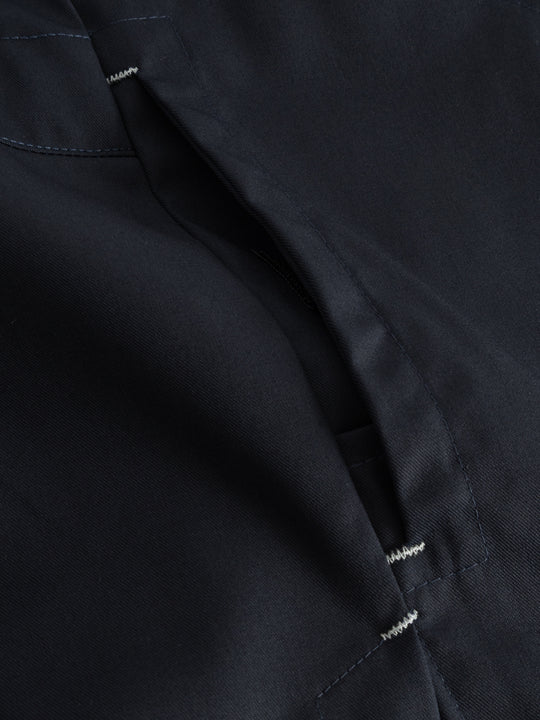 Yksityiskohtakuva tummansinisen työliivin sivutaskusta. 