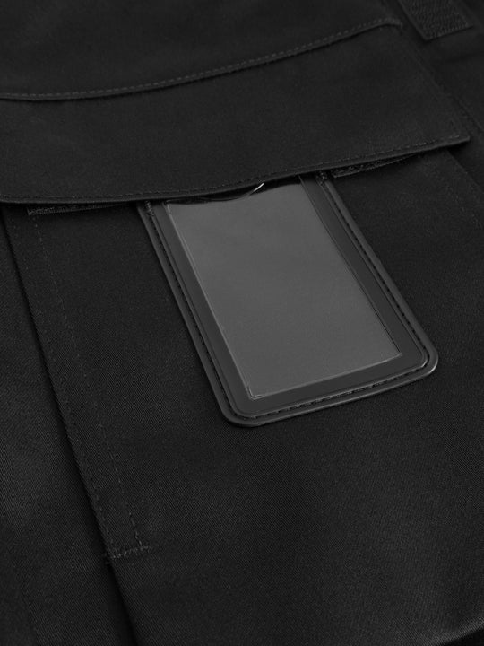 Yksityiskohtakuva mustan palosuojatun työtakin rintataskusta ja käyntikorttikotelosta. 