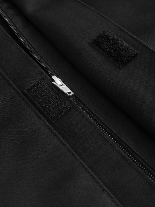 Yksityiskohtakuva mustan palosuojatun työtakin etuvetoketjusta ja listan alla olevasta tarrakiinnityksestä. 