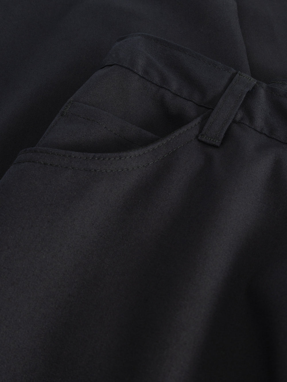 Yksityiskohtakuva tummansinisten naisten työhousujen taskusta. 