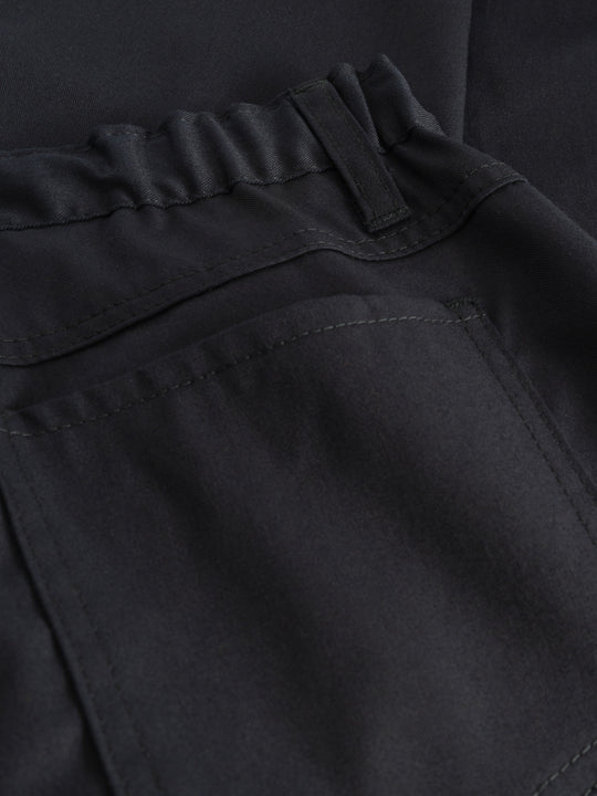 Yksityiskohtakuva tummansinisten naisten työhousujen takataskusta.