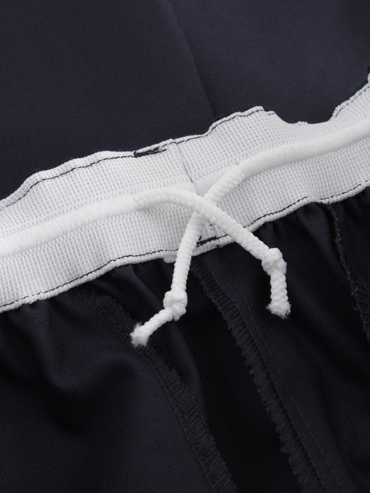 Yksityiskohtakuva tummansinisten housujen vyötäröllä olevasta kiristysnauhasta. 