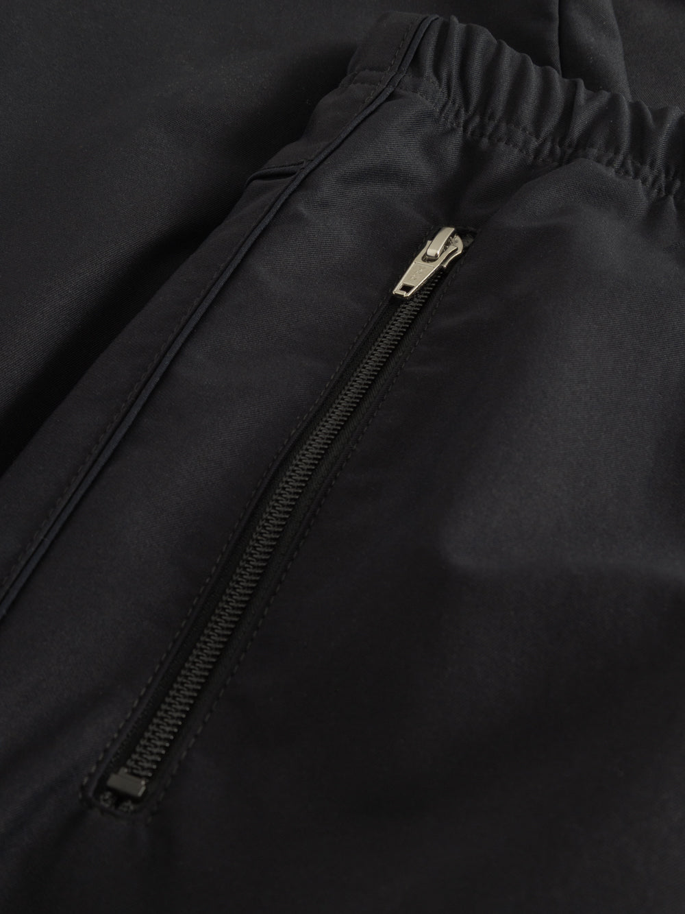 Yksityiskohtakuva tummansinisten housujen vetoketjullisesta sivutaskusta. 