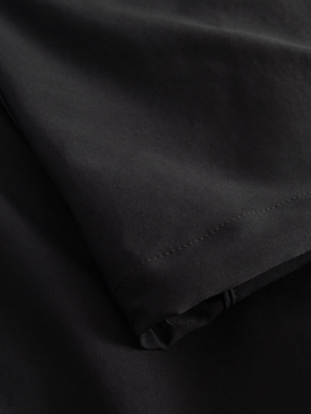 Yksityiskohtakuva tummansinisten housujen lahkeesta. 