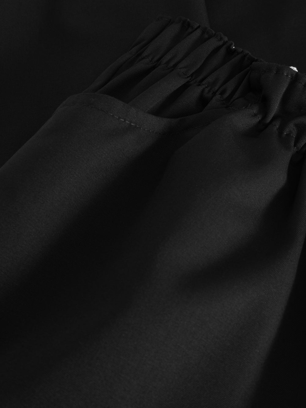 Yksityiskohtakuva mustien kuminauhavyötäröisten sivutaskusta. 