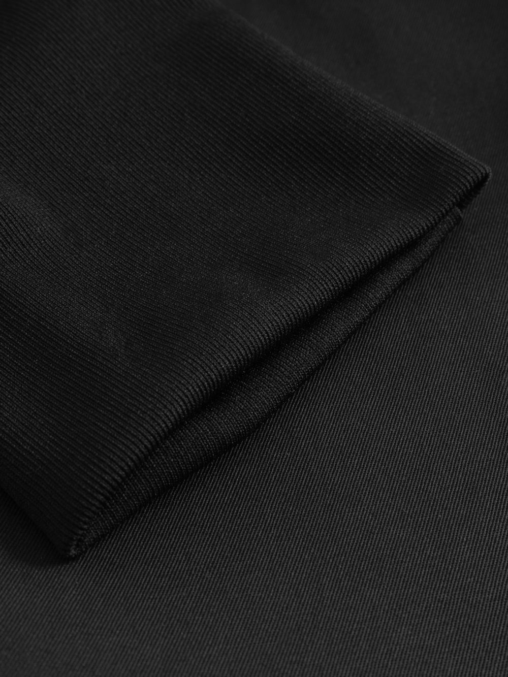 Yksityiskohtakuva mustien kuminauhavyötäröisten housujen lahkeen suun resorista. 