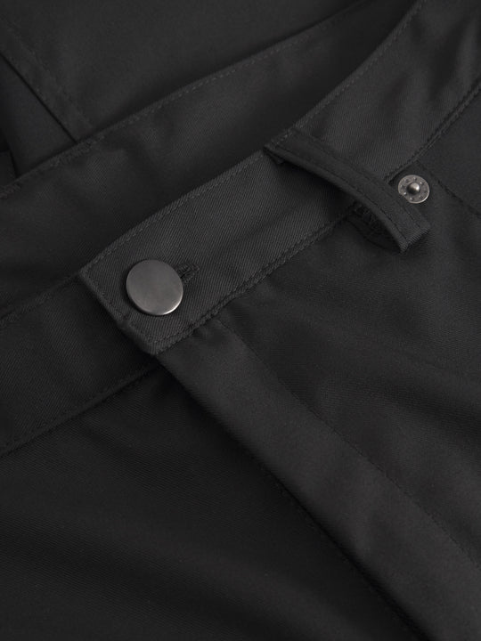 Miesten mustien reisitaskuhousujen vyötäröltä edestä tarkempi yksityiskohtakuva. 