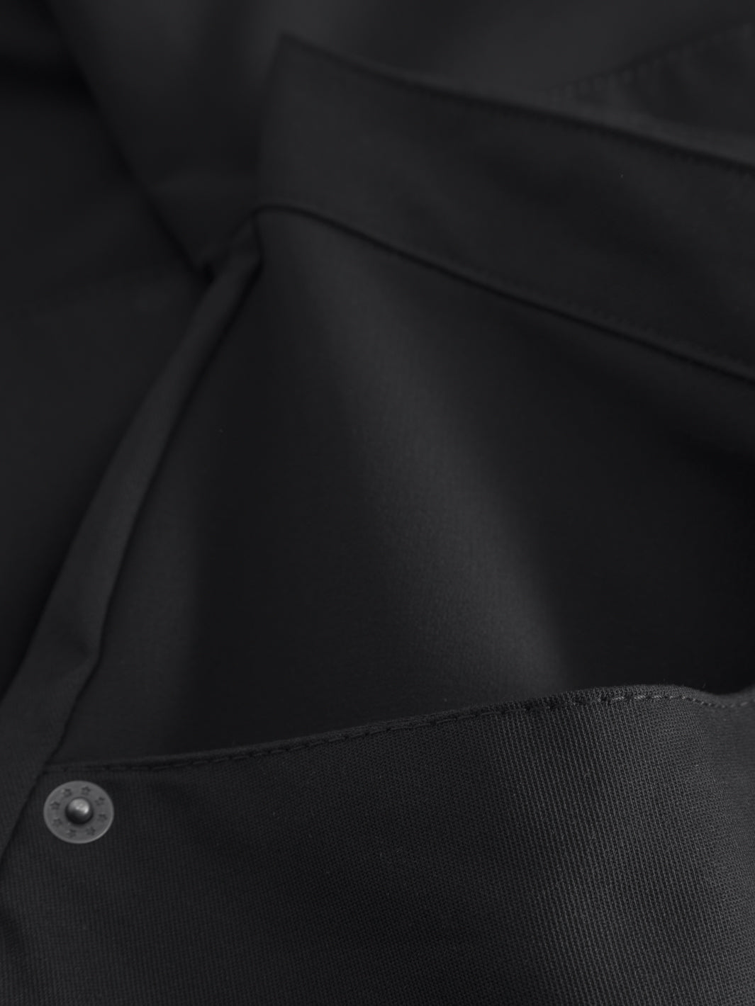 Miesten mustien reisitaskuhousujen sivutaskusta yksityiskohtakuva. 