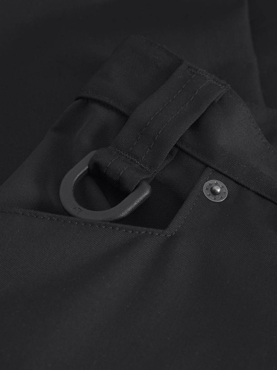 Yksityiskohtakuva mustien reisitaskuhousujen avainlenkistä ja sivutaskusta. 