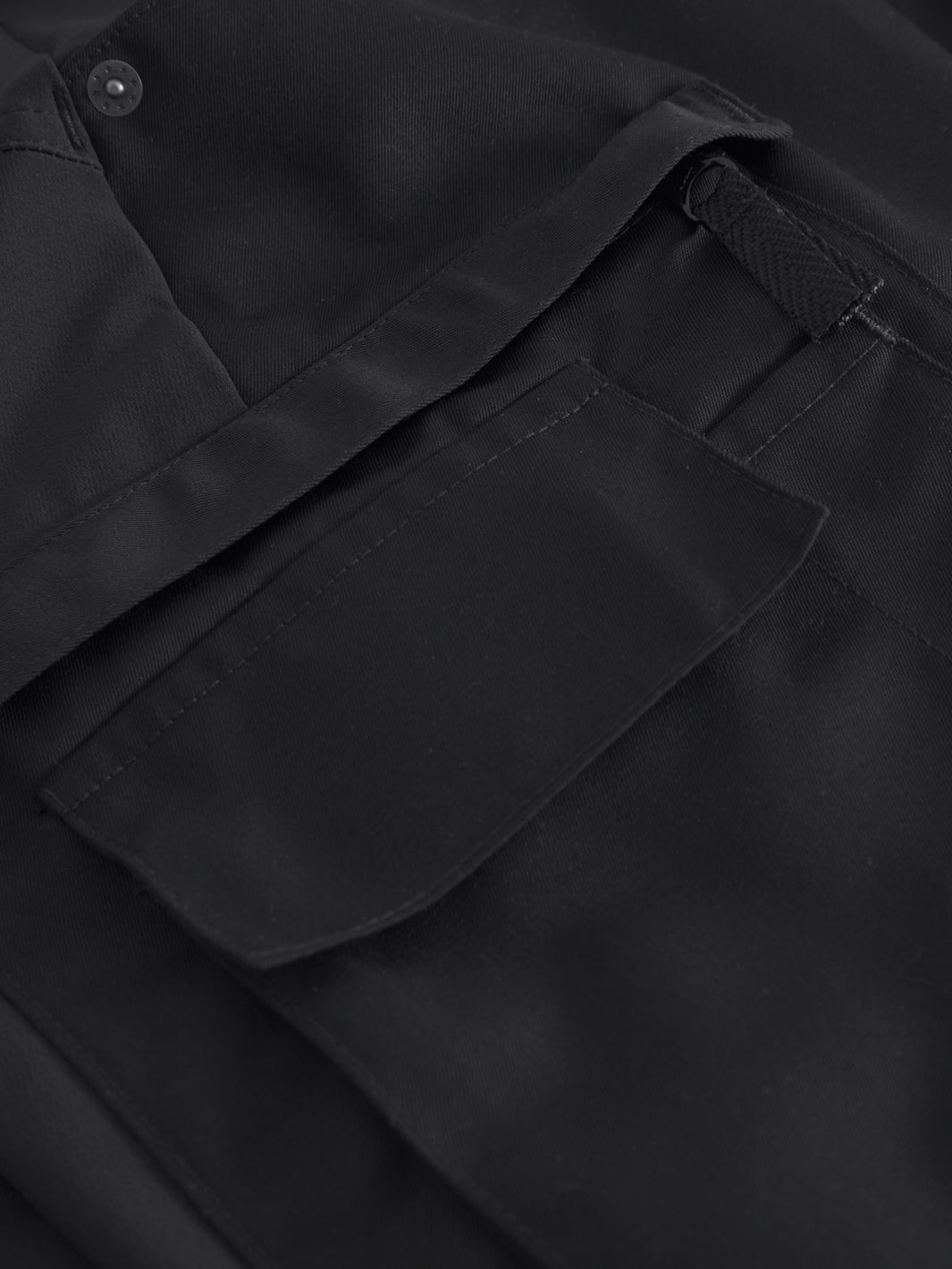 Yksityiskohtakuva mustien reisitaskuhousujen reisitaskuista. 