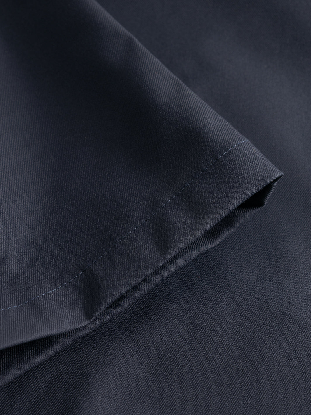 Yksityiskohtakuva tummansinisten housujen lahkeesta. 