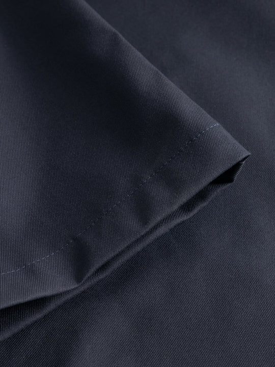 Yksityiskohtakuva tummansinisten housujen lahkeesta. 