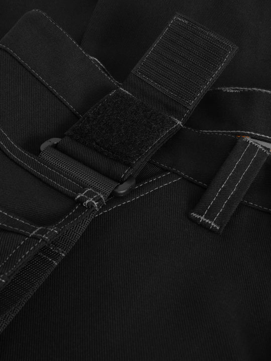 Yksityiskohtakuva mustien työhousujen riipputaskun kiinnityksestä. 