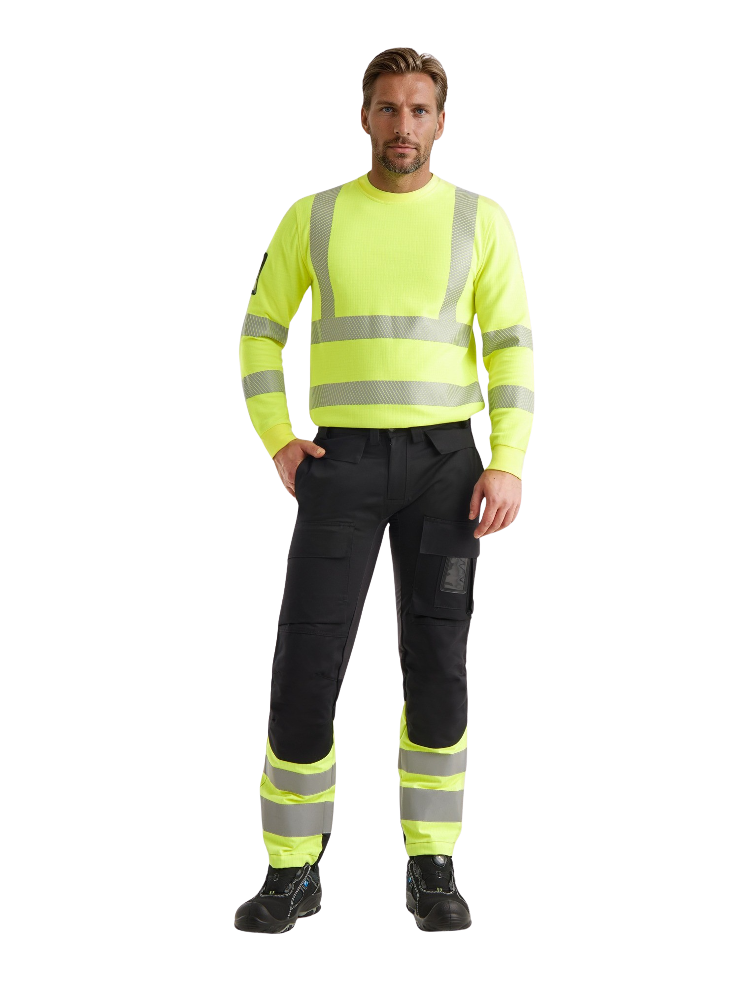 Kuvassa miesmallilla päällä Image Wearin keltainen palosuojattu varoituscollege sekä palosuojatut mustat reisitaskuhousut, joissa keltaiset lahkeet heijastinnauhoilla. 