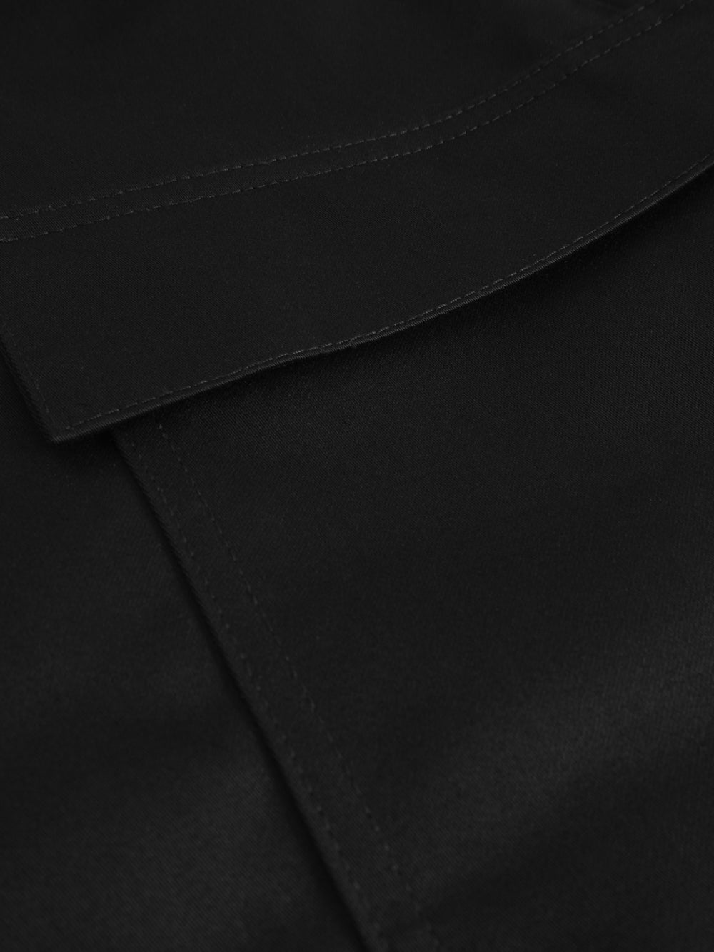 Yksityiskohtakuva mustien palosuojattujen työhousujen taskusta.