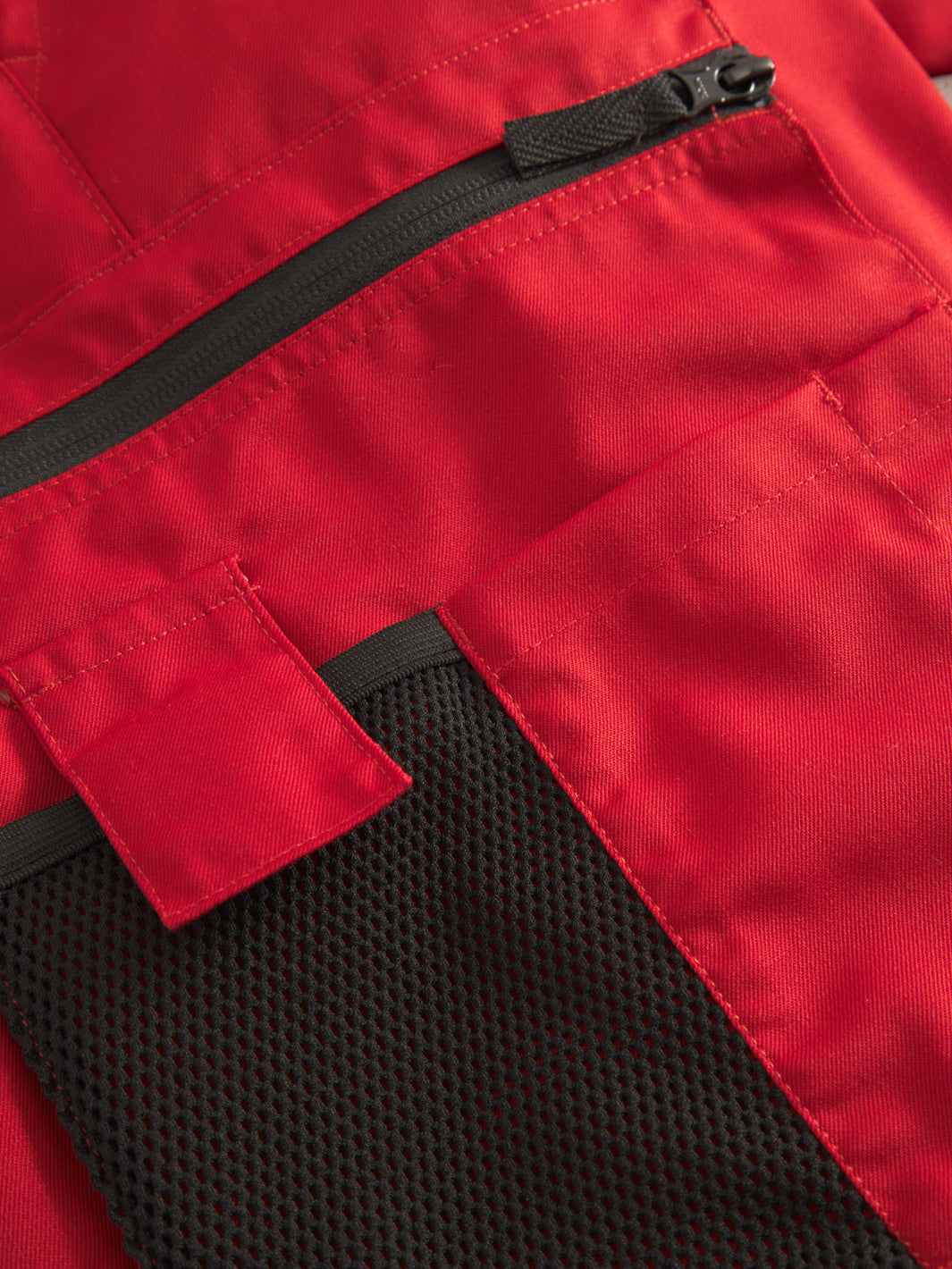 Yksityiskohta punaisten Lanssi-malliston työhousujen vetoketjutaskusta. 