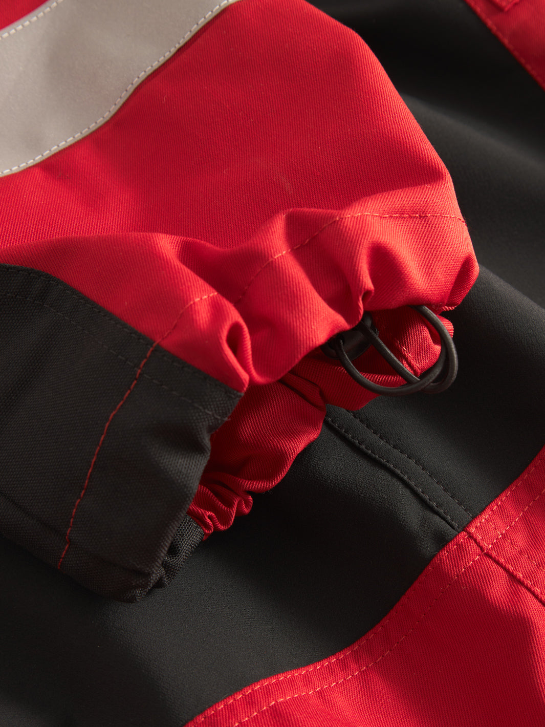 Yksityiskohtakuva punaisten Lanssi-housujen lahkeensuun kiristysnauhasta. 