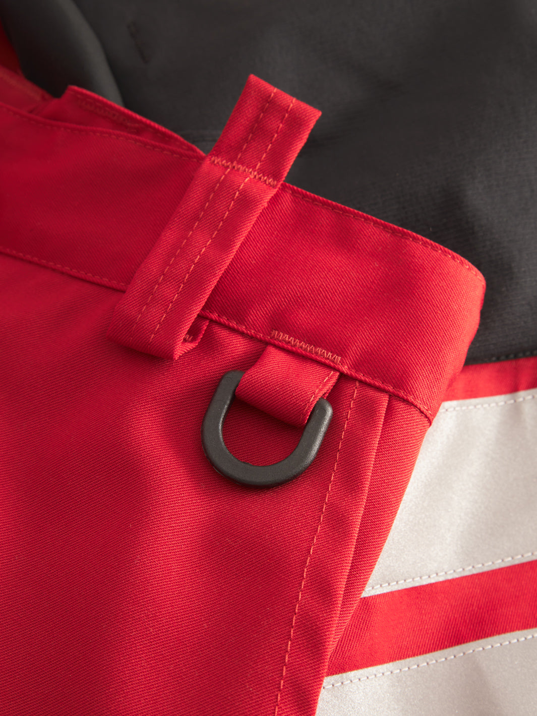 Yksityiskohtakuva punaisten Lanssi työhousujen vyötäröllä olevasta D-lenkistä. 