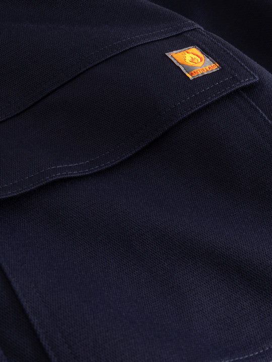 Yksityiskohtakuva tummansinisen palosuojatun työhaalarin taskusta ja antiflame-merkistä. 