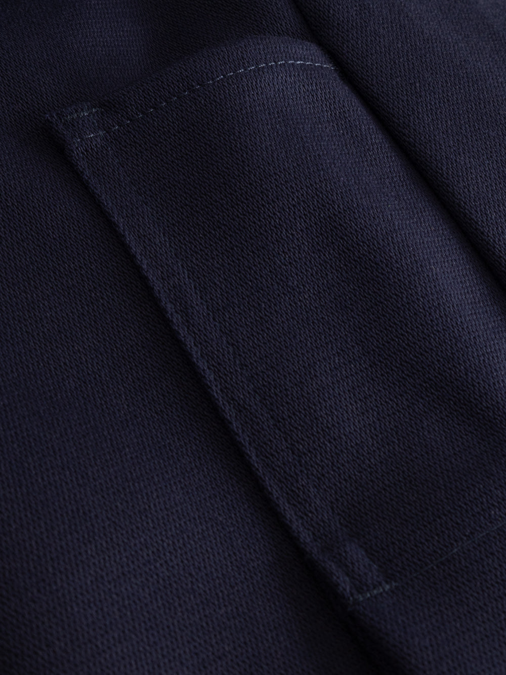 Yksityiskohtakuva tummansinisen palosuojatun työhaalarin taskusta.