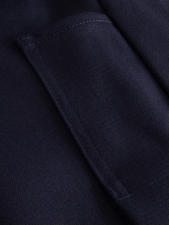 Yksityiskohtakuva tummansinisen palosuojatun työhaalarin taskusta.