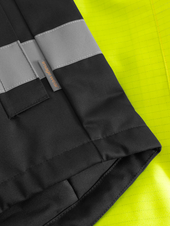 Yksityiskohtakuva keltaisen näkyvän palosuojatun takin helmasta ja sivussa olevasta Image Wearin tuotemerkistä.