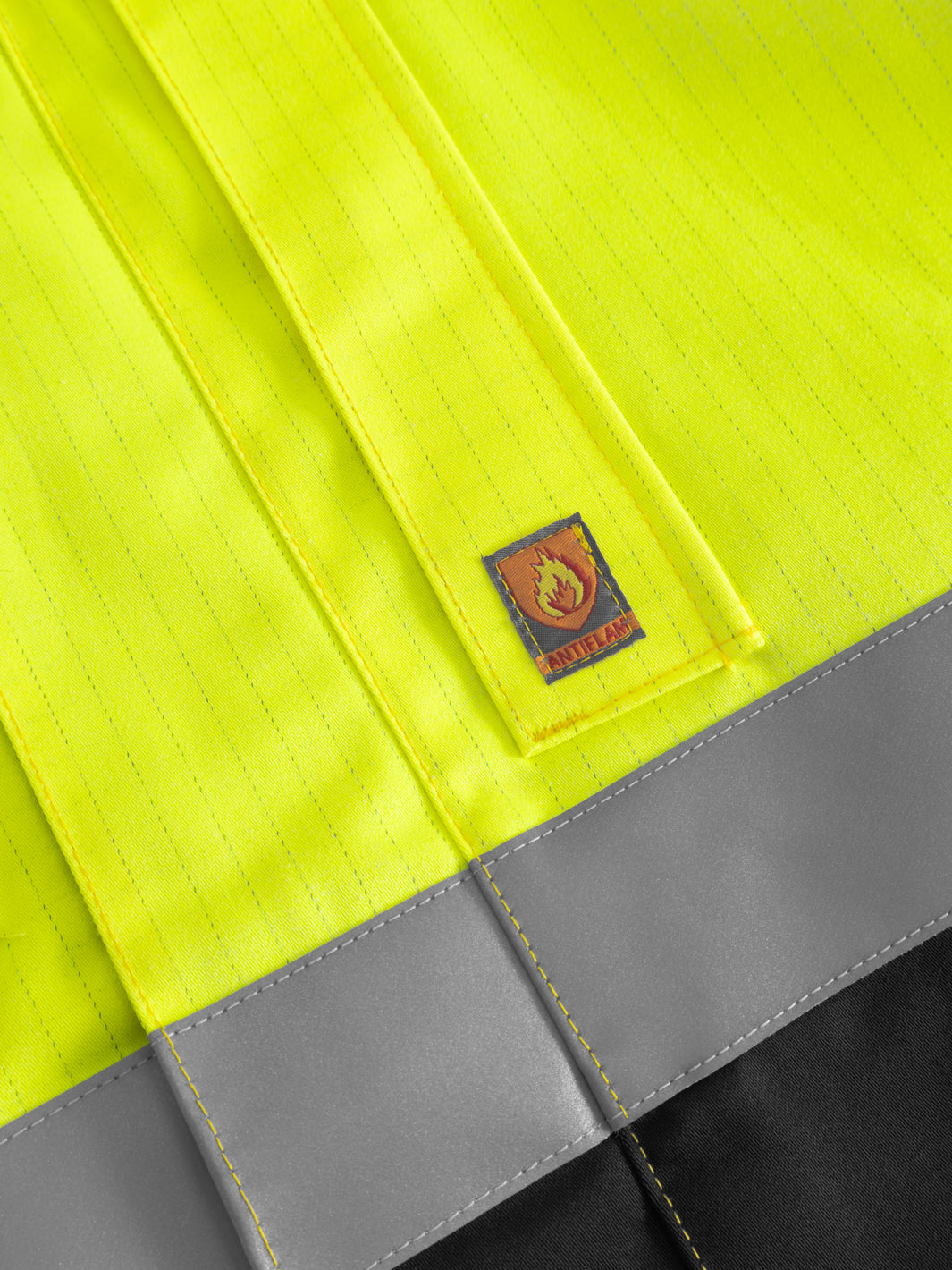 Yksityiskohtakuva palosuojatun takin taskusta ja antiflame-merkistä. 