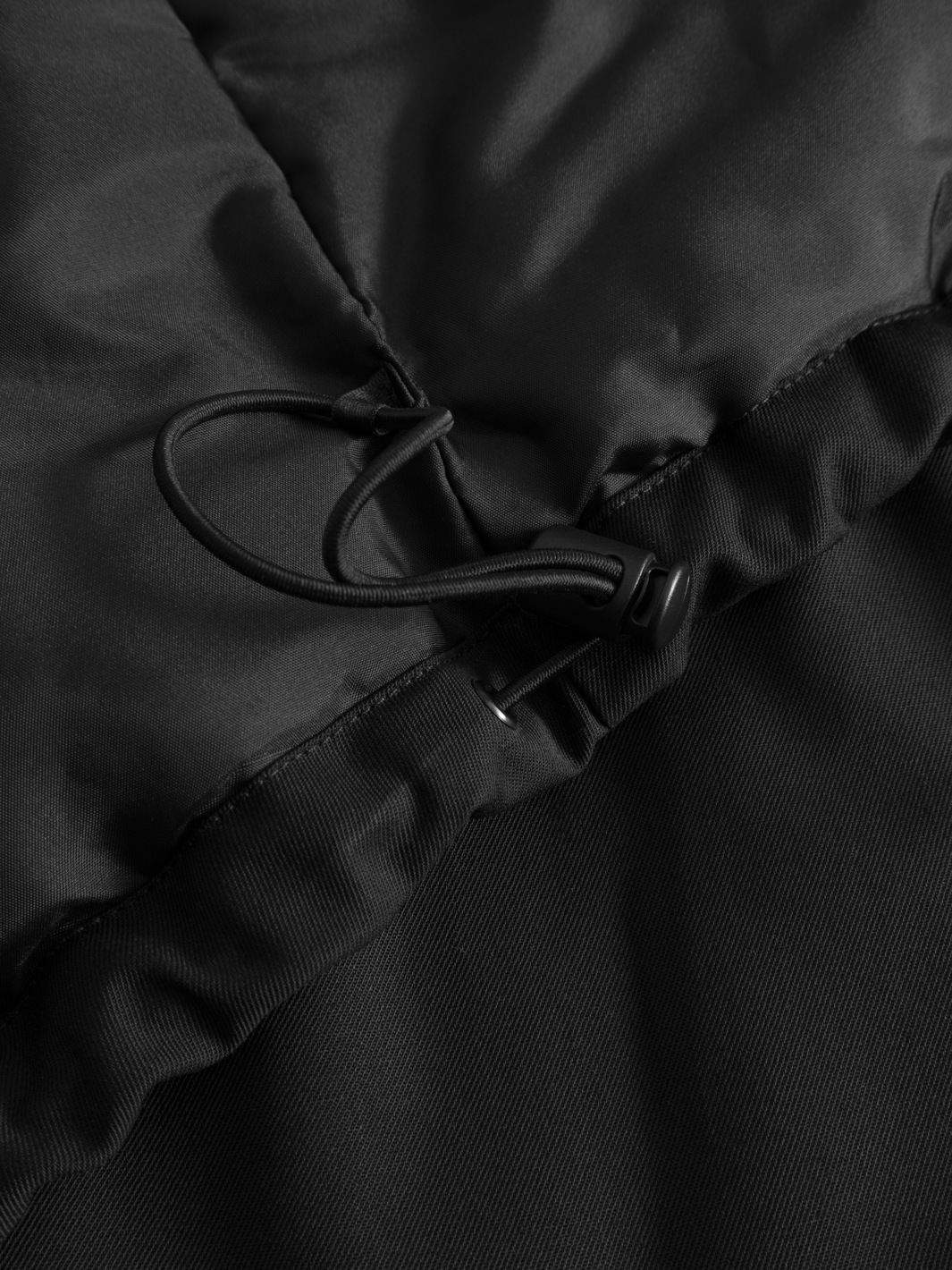 Yksityiskohtakuva mustan naisten Pyry talvitakin kiristysnauhasta takin sivussa sisäpuolella. 