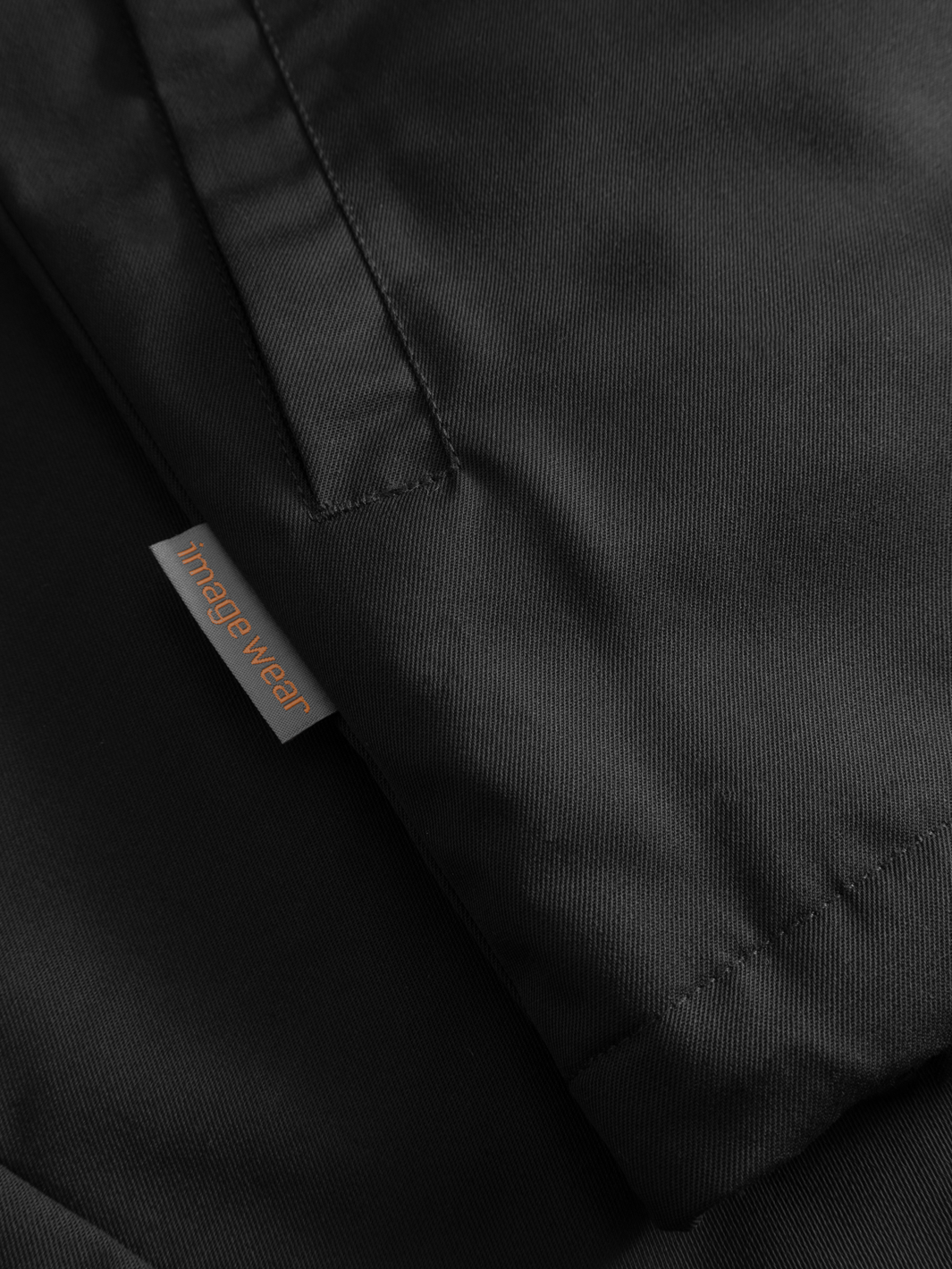 Yksityiskohtakuva mustan naisten Pyry talvitakin sivutaskusta ja sivusaumassa olevasta Image Wearin tuotemerkistä.